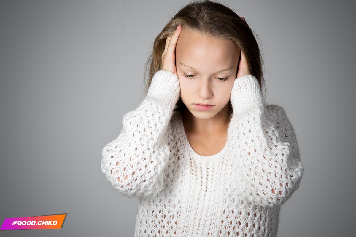 Portrait of unhappy beautiful casual caucasian girl wearing white knitted sweater, holding her head in arms with depressed expression, troubled or feeling pain, studio, gray background, copy space